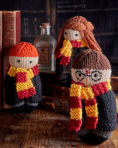 two knitted harry potter dolls sitting next to each other in front of bookshelves