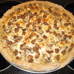 a pizza sitting on top of a metal pan covered in cheese and sausage toppings