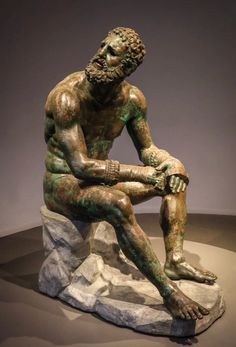 a bronze statue of a man sitting on top of a white and green stone slab