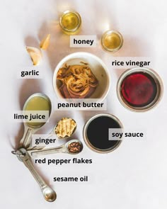 ingredients to make peanut butter and honey on a white surface with spoons, measuring cup, salt shakers, sugar cubes