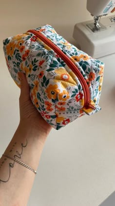 a woman's hand holding a small floral pouch