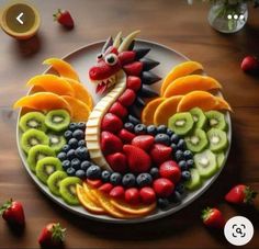 a plate that has fruit in the shape of a rooster on it with strawberries, kiwis and oranges