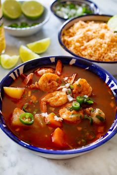 two bowls filled with shrimp and rice next to lime wedges on the counter top