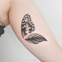 a black and white butterfly tattoo on the left upper arm, with dots in it's wings