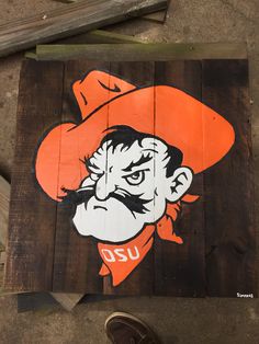 a wooden sign with an image of a man wearing a cowboy hat and orange bandana