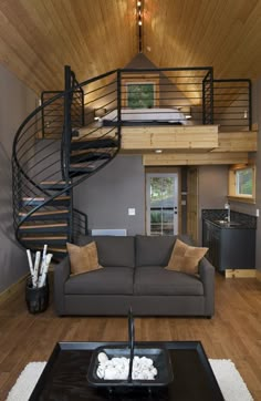 a living room with a couch, coffee table and spiral stair case in it's center