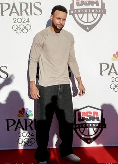 a man standing on top of a red carpet in front of a white wall and logo