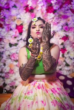 a woman with henna on her hands in front of flowers