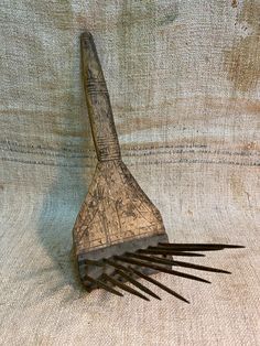 a wooden comb with long black hair sticking out of it's side on a fabric background