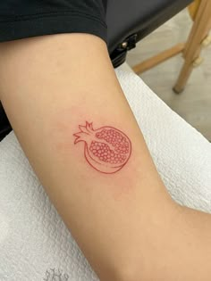 a small pomegranate tattoo on the arm