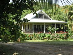 a white house surrounded by trees and flowers