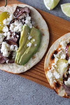 two tortillas with meat, cheese and avocado on a cutting board