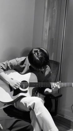 a man sitting in a chair playing an acoustic guitar