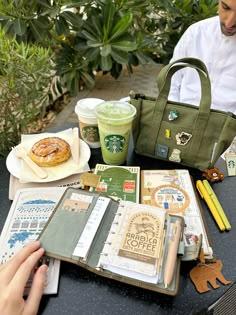 a person sitting at a table with coffee, books and other items in front of them