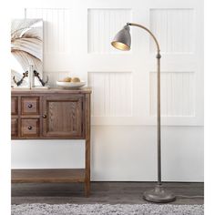 a floor lamp next to a dresser and table