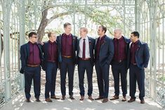 a group of men standing next to each other in front of a metal structure with trees