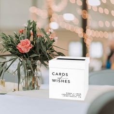 a card box sitting on top of a table next to a vase filled with flowers