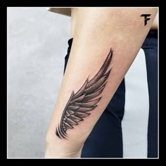 a black and white feather tattoo on the arm