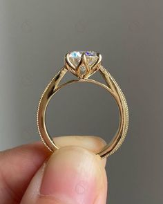 a hand holding a gold ring with two hearts on it