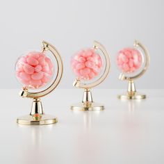 three small globes with pink candy in them