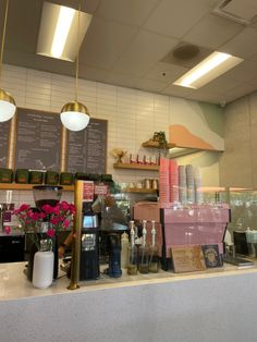 the interior of a coffee shop with flowers and menus on the wall behind the counter