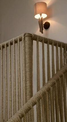 a lamp that is on the side of a roped stair railing with ropes hanging from it