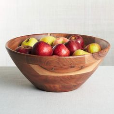 a wooden bowl filled with red and green apples