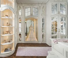 a white closet filled with lots of glass doors and shelves covered in mannequins