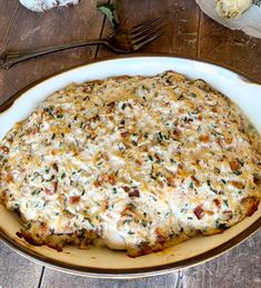 a casserole dish with cheese and other toppings sits on a wooden table