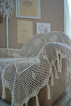 a crocheted blanket is draped over an old couch with tassels on it