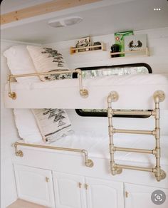 the bunk bed is made up with white sheets and gold metal rails, along with bookshelves