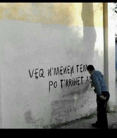 a man standing next to a wall with writing on it