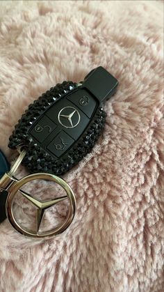 a mercedes keychain is laying on a fuzzy blanket