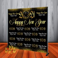 a black and gold new year's card with a clock in the middle on a wooden floor