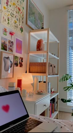 an open laptop computer sitting on top of a white desk next to a lamp and window