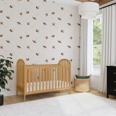 a baby's room with a crib, dresser and wallpaper that has birds on it