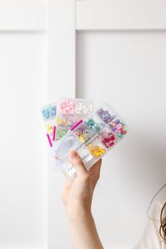 a woman holding up several small plastic buttons