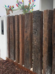 a white microwave sitting on top of a wooden fence next to a flower pot filled with flowers