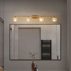 a bathroom with a sink, mirror and lights on the wall above it's counter