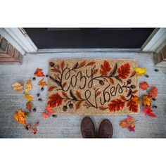 a door mat with the words happy fall written on it and leaves scattered around it