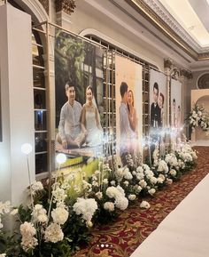 a long table with flowers and candles on it in front of a large photo wall