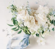 a bridal bouquet with white flowers and blue ribbon on the side, against a white background