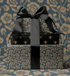 two wrapped gift boxes sitting on top of a blue and gold wallpaper covered table