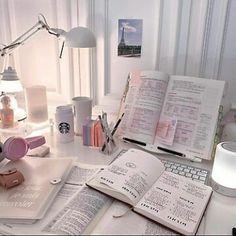 an open book sitting on top of a desk next to a computer keyboard and lamp