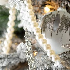 a silver and white christmas ornament sitting on top of a tree