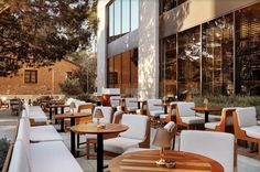 tables and chairs are lined up in front of a building with large windows on both sides