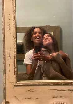 two people taking a selfie in front of a mirror