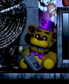 a teddy bear wearing a party hat and holding a remote control in front of a computer screen