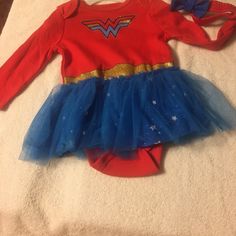 a red shirt and blue tutu skirt with wonder logo on it sitting on a white blanket