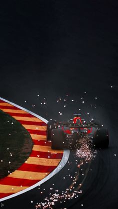 a red and white race car driving on a track with fireworks coming out of it